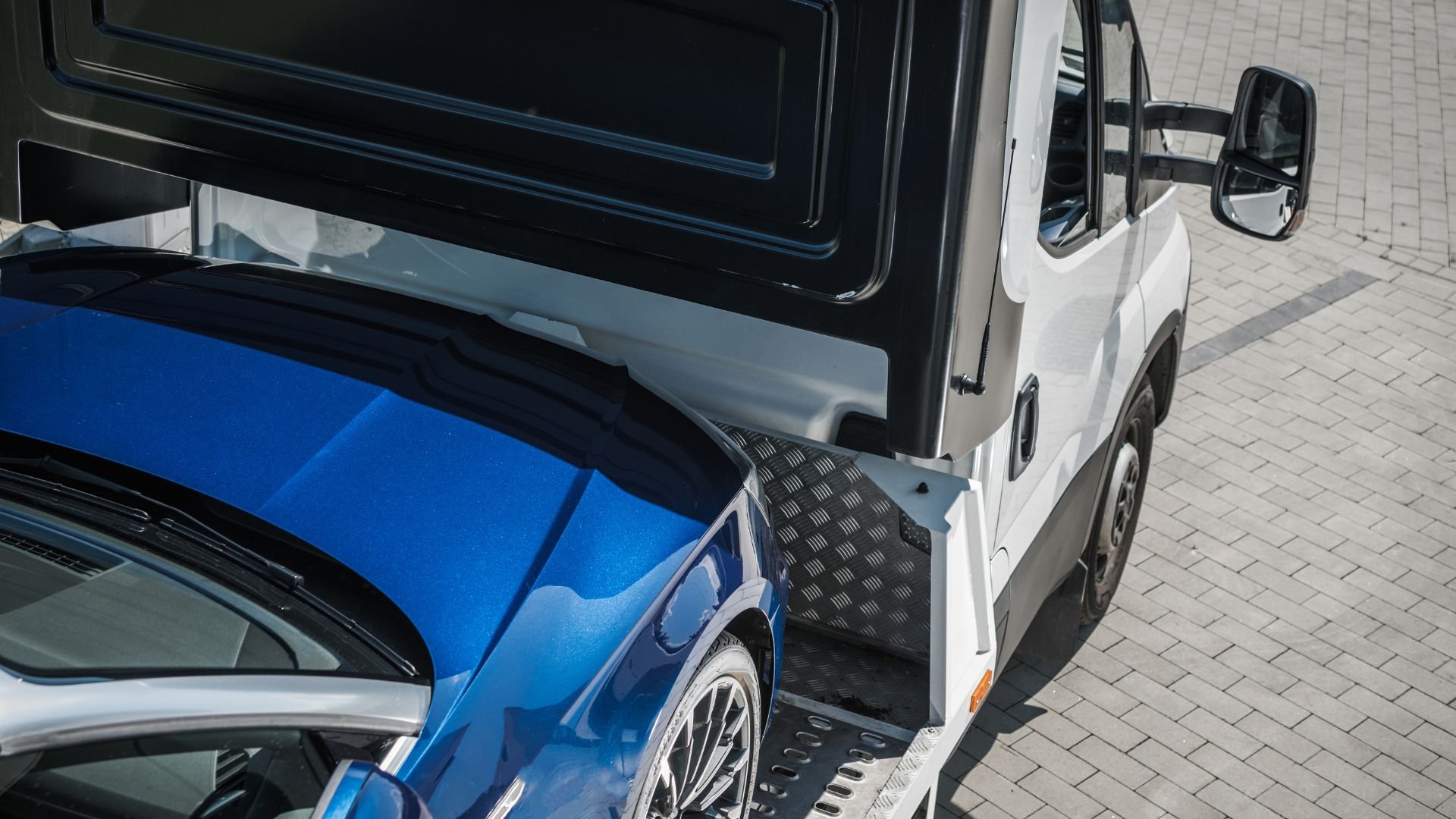 Blue sports car being loaded onto a white tow truck or trailer