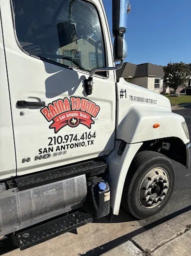 White tow truck with logo parked on street in San Antonio, Texas