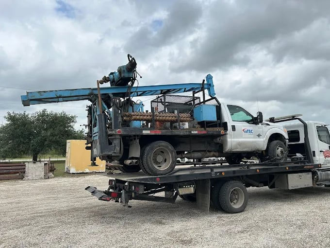 Tow truck transporting a white utility truck with industrial equipment