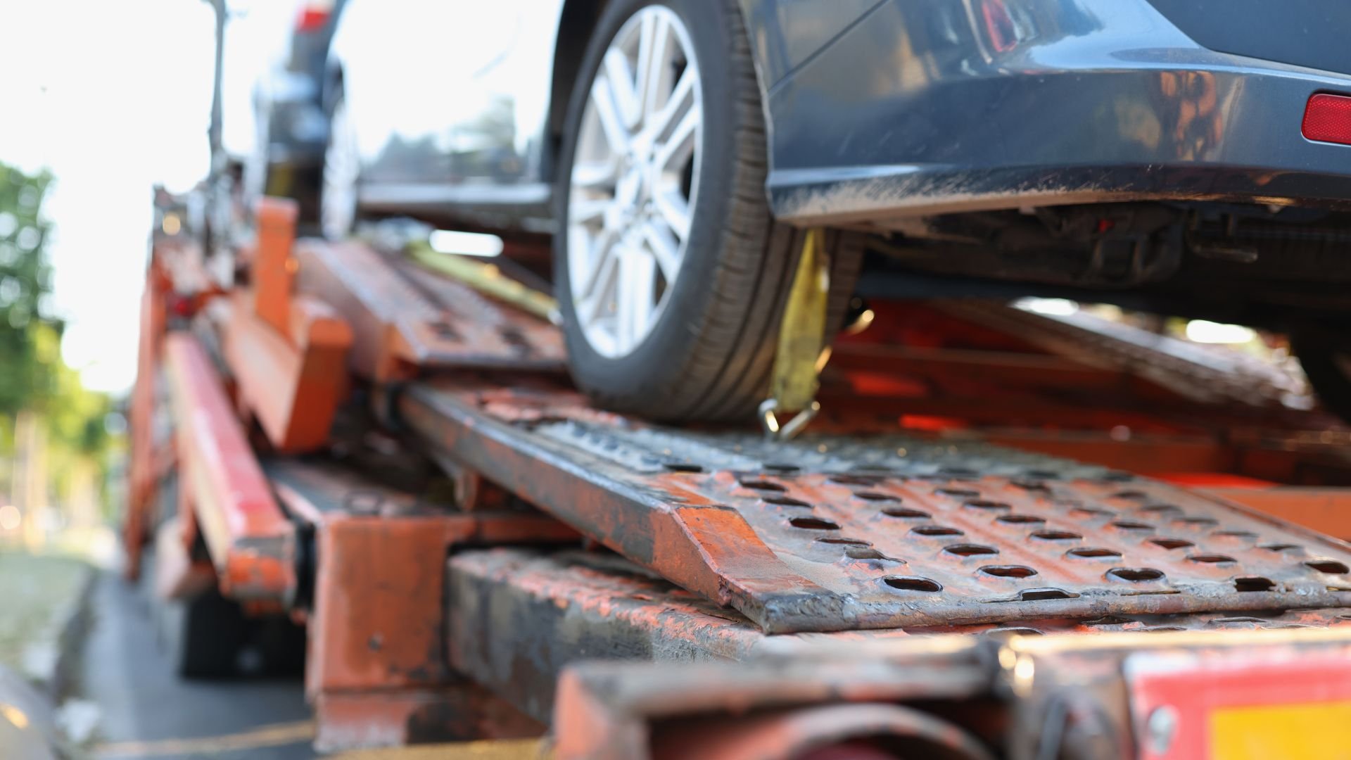 Car being loaded onto a rusty, old tow truck flatbed